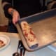 Rolling the tortillas and placing them in the baking pan.