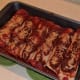 Covering the enchiladas with sauce and vegan cheese.