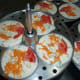 Rava idli batter with carrot, cashew nuts, and tomato topping.