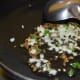 Step two: Saute cumin seeds till they crackle. Add chopped garlic and green chilies. Saute for a minute.