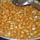 Step eight: Once you get the proper consistency, add peanuts into the jaggery syrup. Boil together for 1 minute.