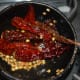 Step three: Saute white lentils, coriander seeds, and red chilies in oil. Turn off the stove when lentils turn golden brown.