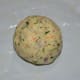 Step 2: Take a lemon-sized chunk of the dough and make a ball. Place it on a greased plastic sheet. Evenly spread the dough with greased fingers to make a 6 inch diameter disc. Make 2–3 holes on it. This will make the cooking faster.
