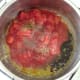 Canned tomatoes and seasonings are added to garlic and oil