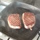 Pork steaks are turned to fry on second side