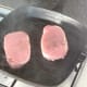 Pork steaks are laid in griddle pan