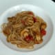 Spaghetti in sauce is plated as a bed for the chicken