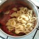 Pasta is added to tomato sauce