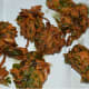 Step three: Take small portions of the batter, press them a little, and slide them into the hot oil. Fry them until golden brown and crispy. Transfer the fried pakoras to an absorbent paper towel.