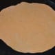 Step four: Take one portion, gently knead, and make a patty. Dust it with maida and roll it thin to make a large disc.