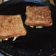 Flip the slices so they are spread-side-down. Add a few drops of butter or oil on the edges and cook covered for 1 minute. Cook on a medium-low fire uncovered for an additional 1 or 2 minutes.