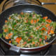 Cooking the fenugreek leaves into the veggies.