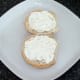 Cream cheese is spread on bread roll