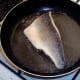 Sea bass fillet is turned to fry gently on skin side