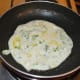 Heat a griddle and grease it with oil or ghee. Put a ladle full of the batter into the canter of the pan and spread it a little. Add a few drops of oil or ghee to the top. Leave the heat on medium. Cover the pan.