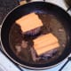 Cheese is laid on top of cooked burgers
