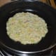 Pour a ladle full of batter on the greased pan or griddle. Spread it a little. Add a few drops of oil on the surface and the edges. Cover the pan. Leave the heat on medium.