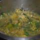 Brinjal/eggplant sambar boiling in a vessel.