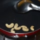 Step two: Roast cashew nuts in oil. Collect them in a bowl.