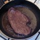 Steak is turned to fry on second side