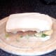 Top is placed on smoked salmon, salad and crisps sandwich