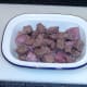 Steak and venison sausage is arranged in pie dish