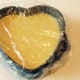 The springform filled with mango peanut butter mixture covered with cellophane ready to be put in the fridge for a few hours or for overnight setting.