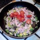 Halved tomatoes are added to sauteed bacon and sprouts