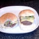 Biting in to cheeseburger with fried sprouts and onion