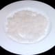 Cooked rice is spread out on a plate to cool