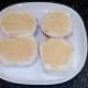 Mustard is spread on cut bread rolls