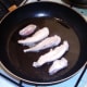 Chicken strips are turned to fry on second side