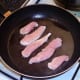 Seasoned chicken strips are added to hot fryin gpan