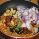 Throw in dry red chilies, curry leaves, chopped ginger, coriander seeds, and chopped onions. Continue sautéing until onions become translucent.