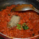 Step five: Throw in mixed Italian herbs, chopped basil, red chili powder, pepper powder, and remaining salt.