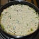 Step six: Spread the tempering evenly. Pour the handvo batter in the center. Spread it a little and flatten the top. Add some sesame seeds on the top.