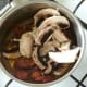 Sliced mushrooms are added to cooked down tomatoes
