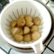 Halved potatoes are cooked by boiling then drained and allowed to steam off and cool