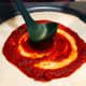 Spread the sauce evenly on the dough.
