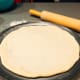 Transfer the rolled-out dough onto the pizza baking pan.