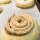 Use a piping bag to pipe the coffee topping on every dough ball. Use a spiral motion.