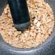 Add the peanuts into the mortar.