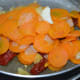 Step four: Open the cooker lid when the steam escapes completely. Strain the carrot mixture. Collect the liquid in a deep-bottomed pan. Put the dry carrot mixture to a blender. Add chopped apple.