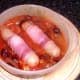 Casseroled chicken sausages in bacon