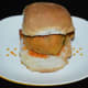 Slit a pav bun horizontally but do not cut all the way through. Spread garlic chutney powder in the slit and then place a potato vada inside.