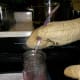Steaming hot grape juice goes into a jar and is immediately capped.