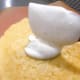 Use a spatula to spread the frosting on top of the first cake.