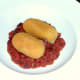 Cocktail sausage potato croquettes are laid on beans in tomato sauce