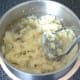 Potatoes are mashed with a hand masher