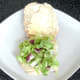 Salad bed is arranged on bottom half of buttered bread roll